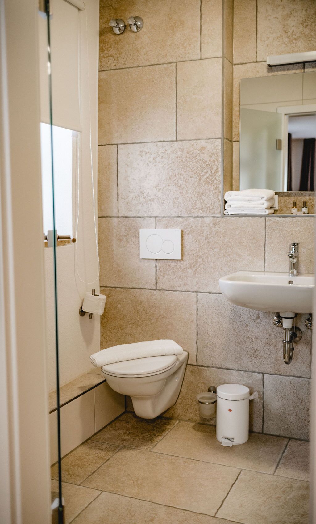 Un baño con inodoro, lavamanos y un cubo de basura pequeño.