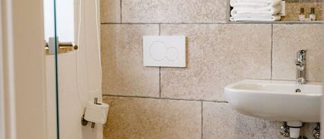 A bathroom with a toilet, sink, and a small trash bin.