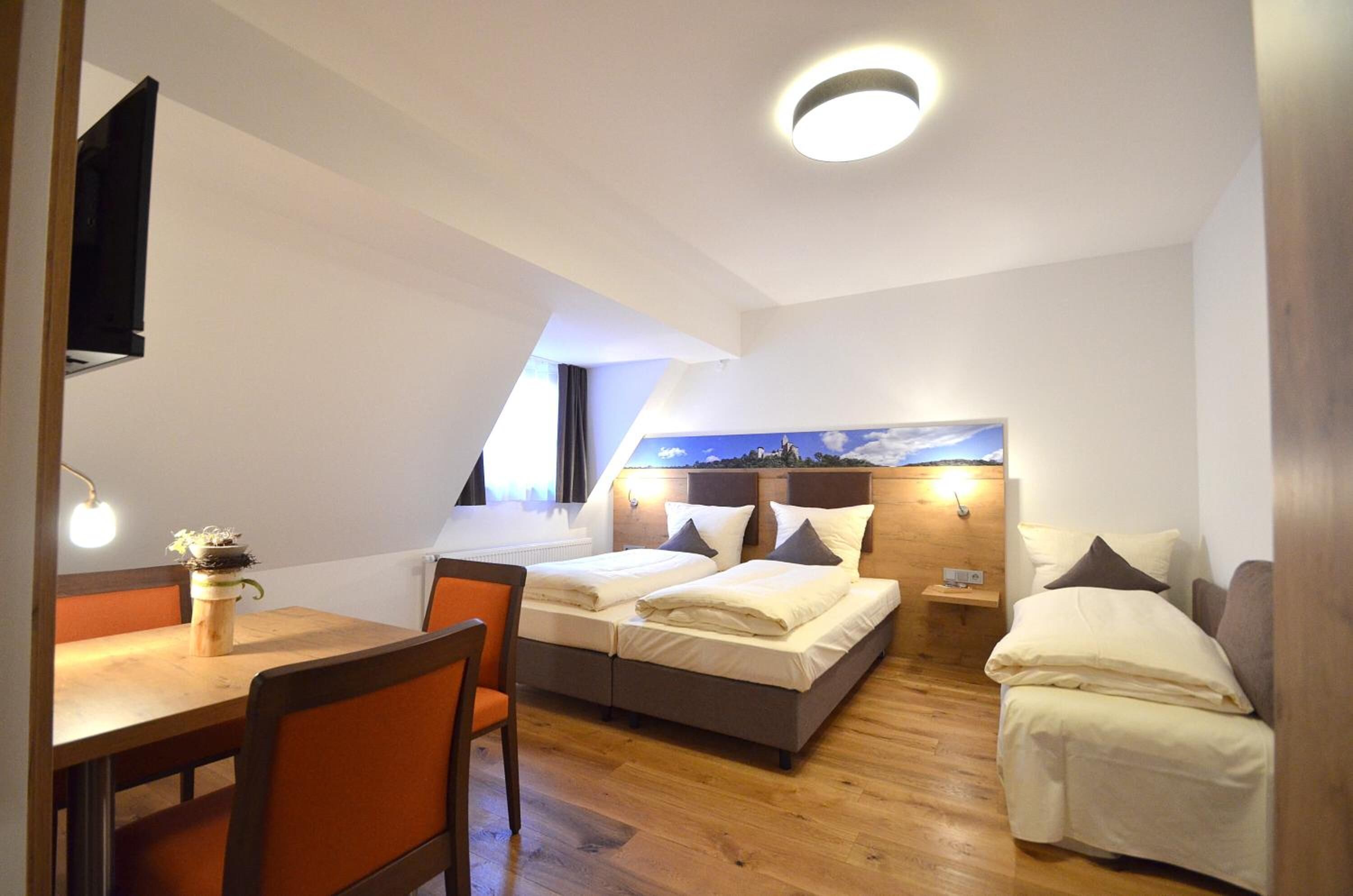 Ein kleines Zimmer mit zwei Betten, einem Esstisch und einem Fernseher.