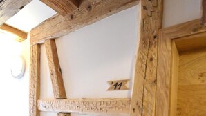 A room with exposed wooden beams and a door with a number '11' sign. - BAUER Gästezimmer (Kipfenberg)