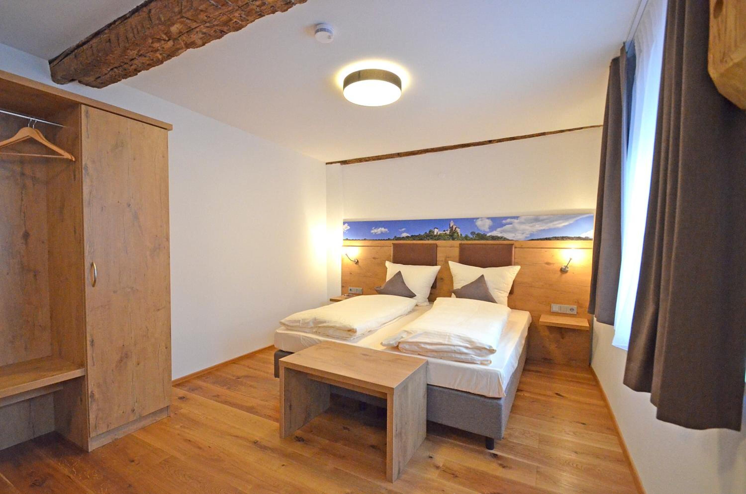 Une chambre avec deux lits, des meubles en bois, un tableau au mur et une armoire.