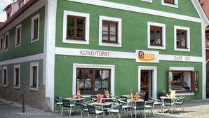A green building with multiple windows and a sign that reads "KONDITORFELI BAUER CAFE EIS". - BAUER Gästezimmer (Kipfenberg)
