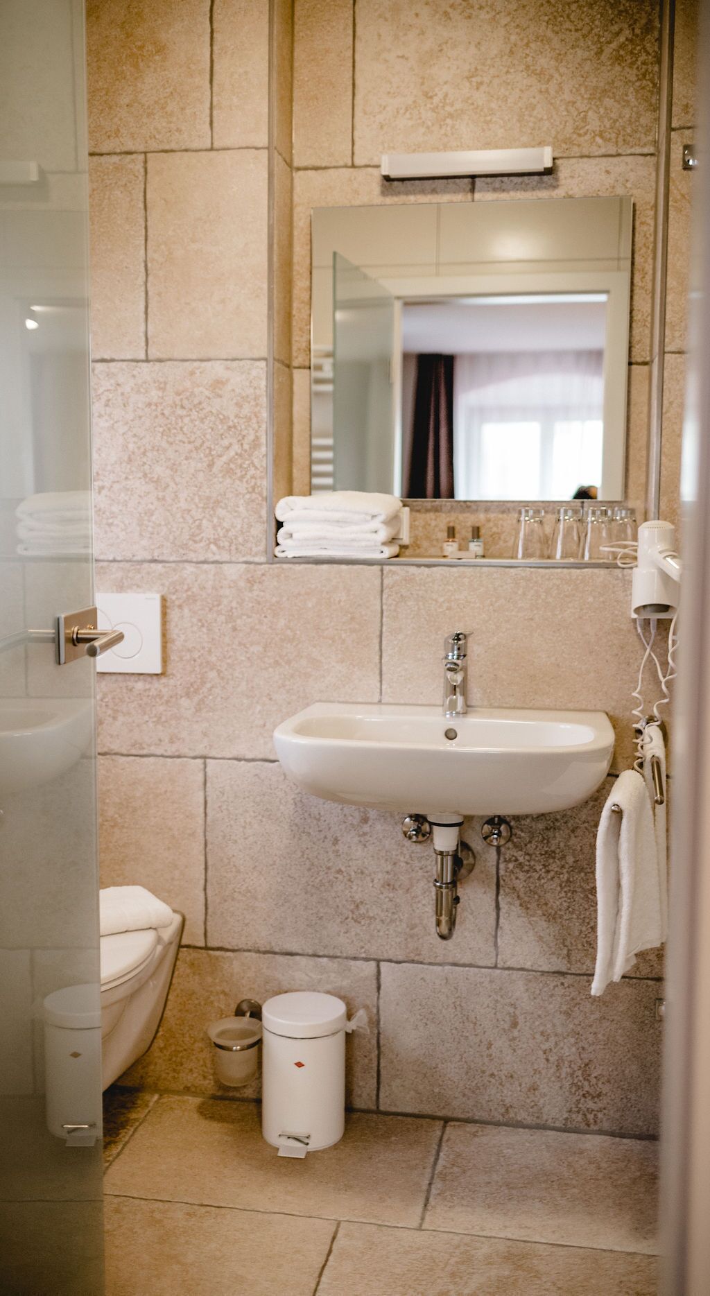 Un baño con lavamanos, espejo y dos inodoros.