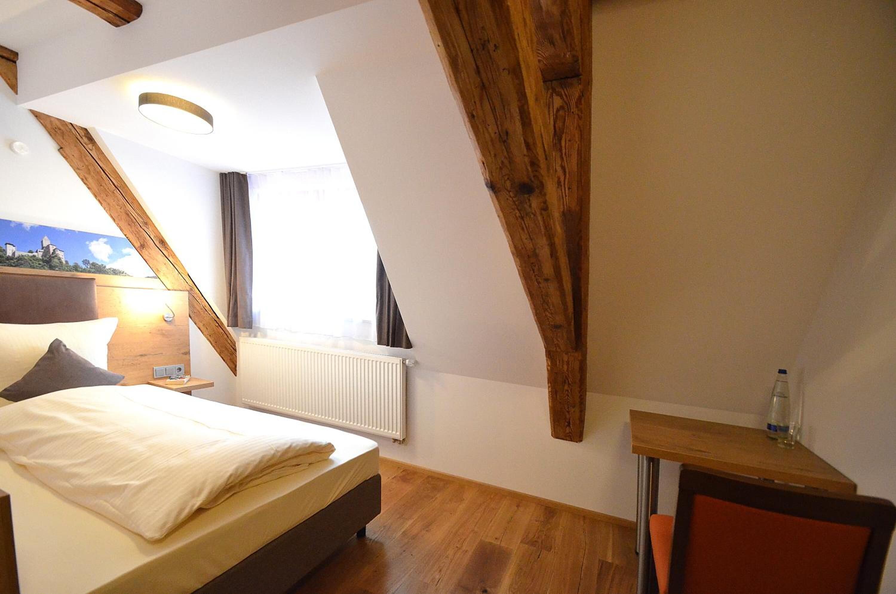 A bedroom with a bed, a nightstand, a table, and a chair.