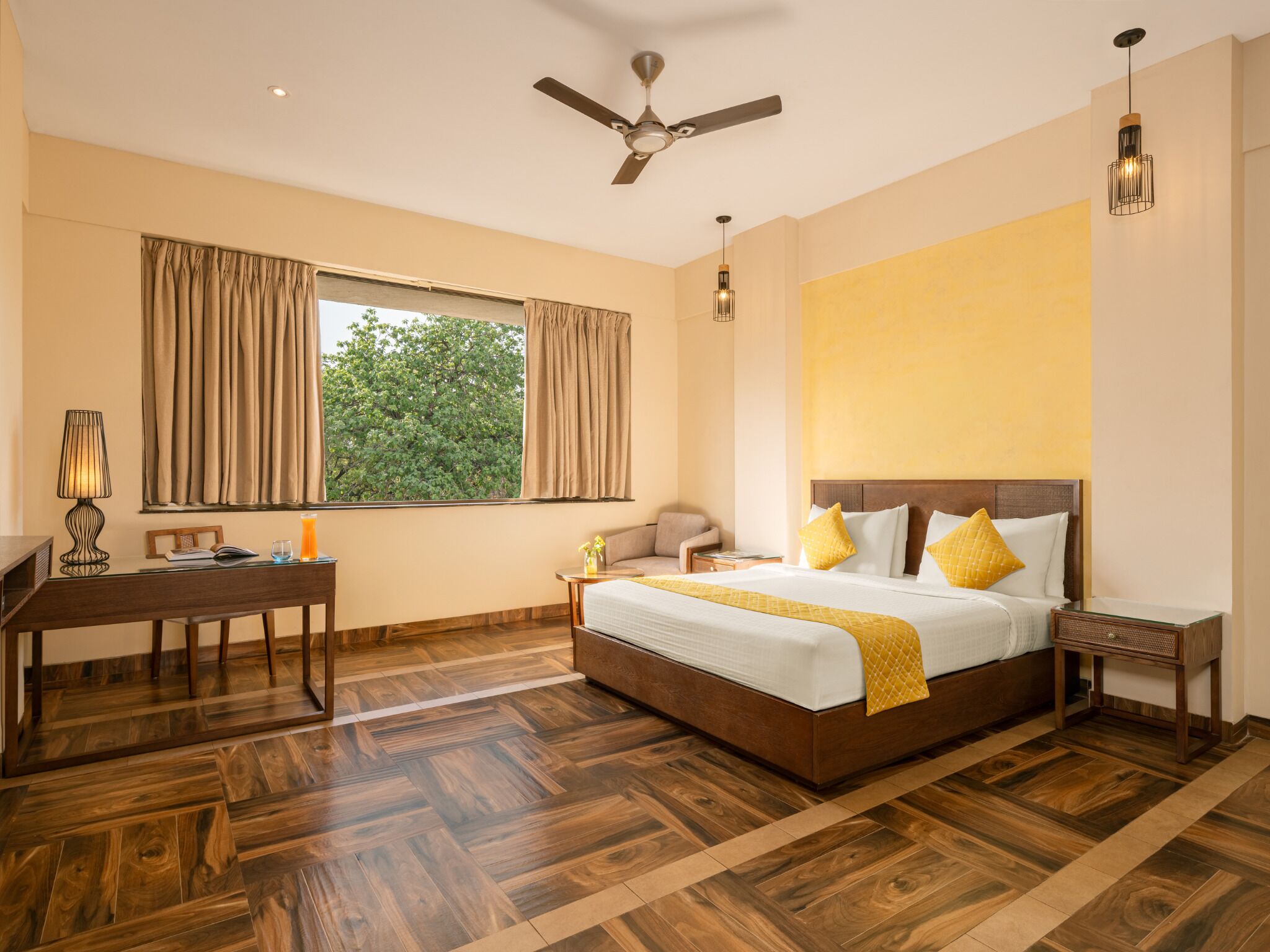 A hotel room with a large bed, a desk, a chair, a lamp, and a ceiling fan.