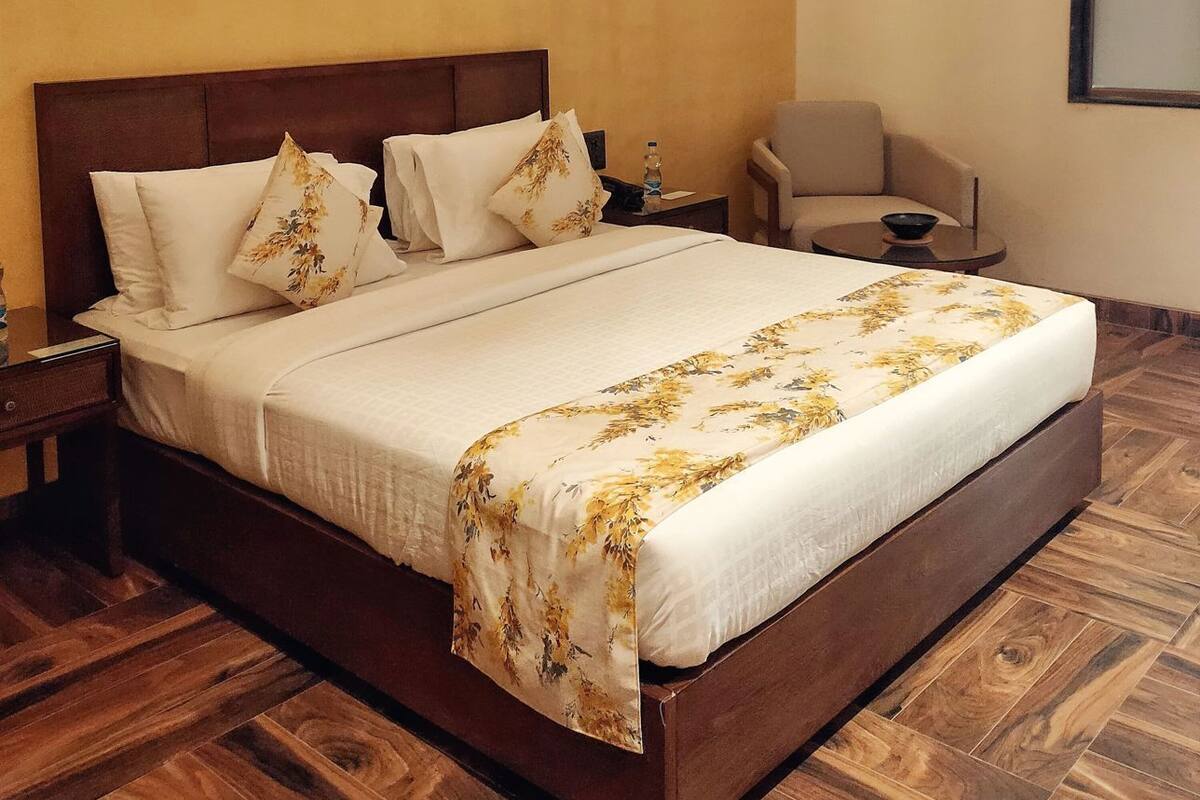 A hotel room with a wooden bed, a nightstand, a chair, and a large window.