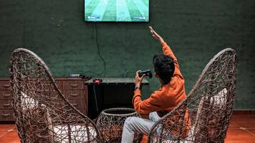 Eine Person sitzt in einem Korbstuhl und spielt ein Videospiel auf einer Konsole.