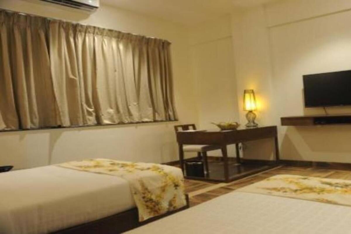 A hotel room with a bed, a desk, a chair, a television, and a window with curtains.