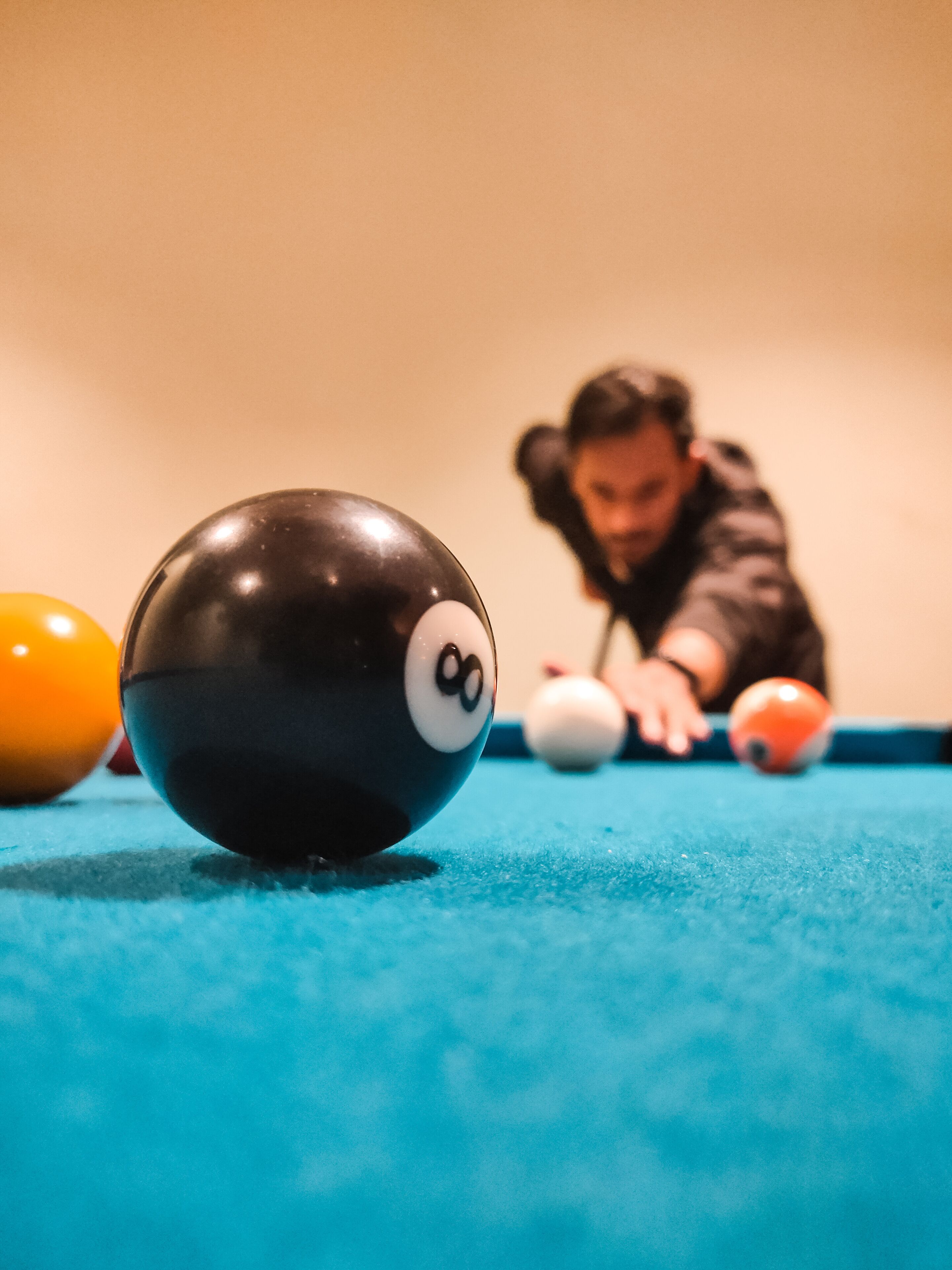 Een close-up van een biljartbal op een pooltafel, met een persoon op de achtergrond.