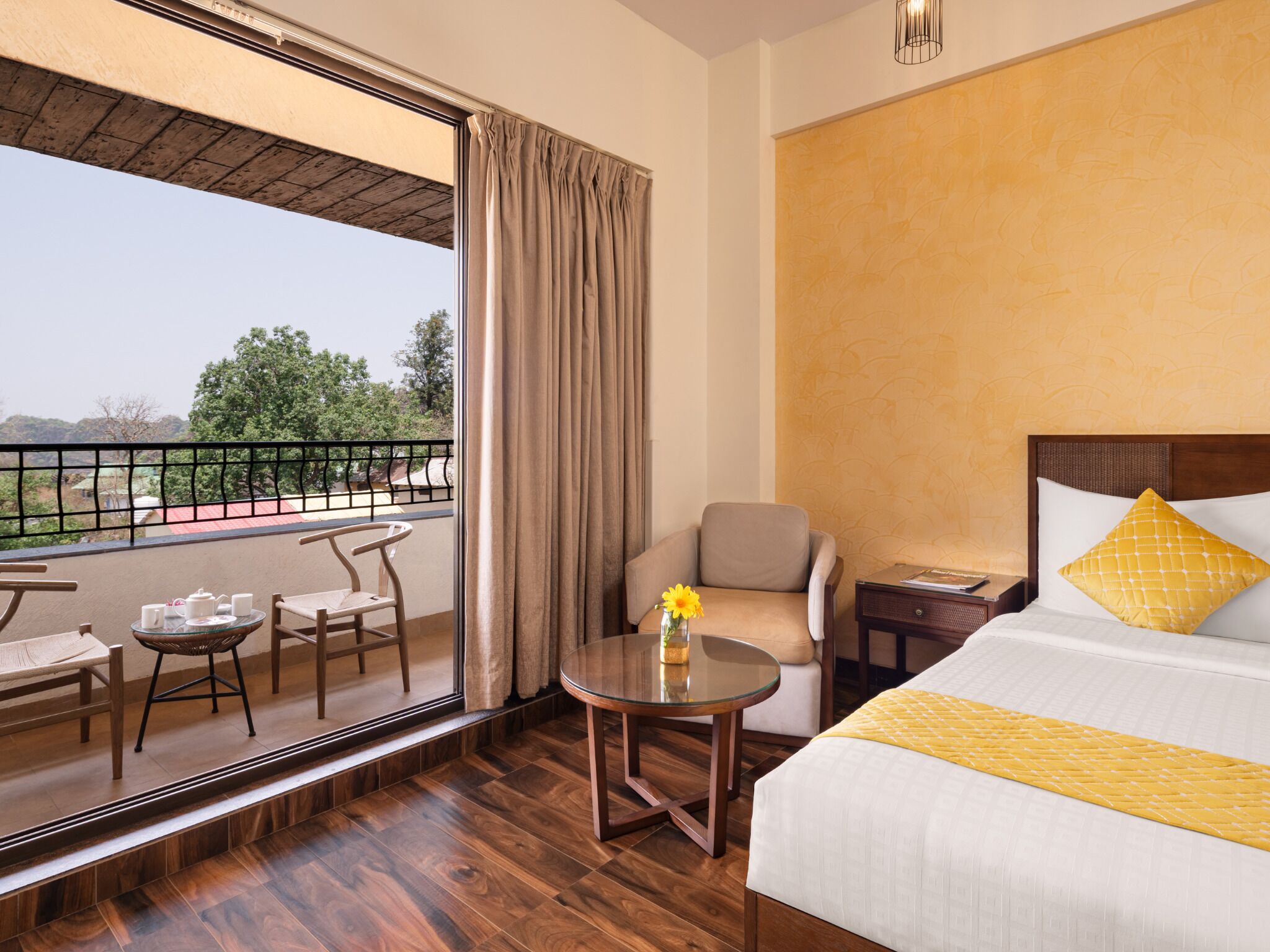 A hotel room with a balcony, a bed, a chair, a table, and a nightstand.