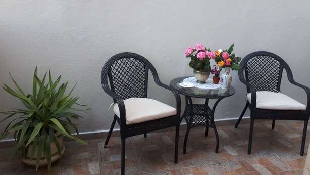 Two wicker chairs with cushions, a small round table with a lace doily, and a potted plant. - B&B Da Andreina (Guspini)