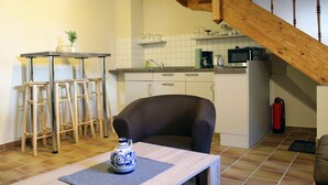 A kitchen with a wooden staircase, a dining table with a vase, and bar stools. - Appartments Tilia (Quedlinburg)