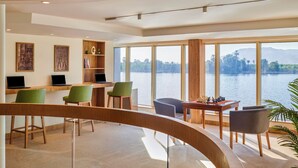 Une chambre moderne équipée d’un bureau, de chaises et offrant une vue sur un lac.