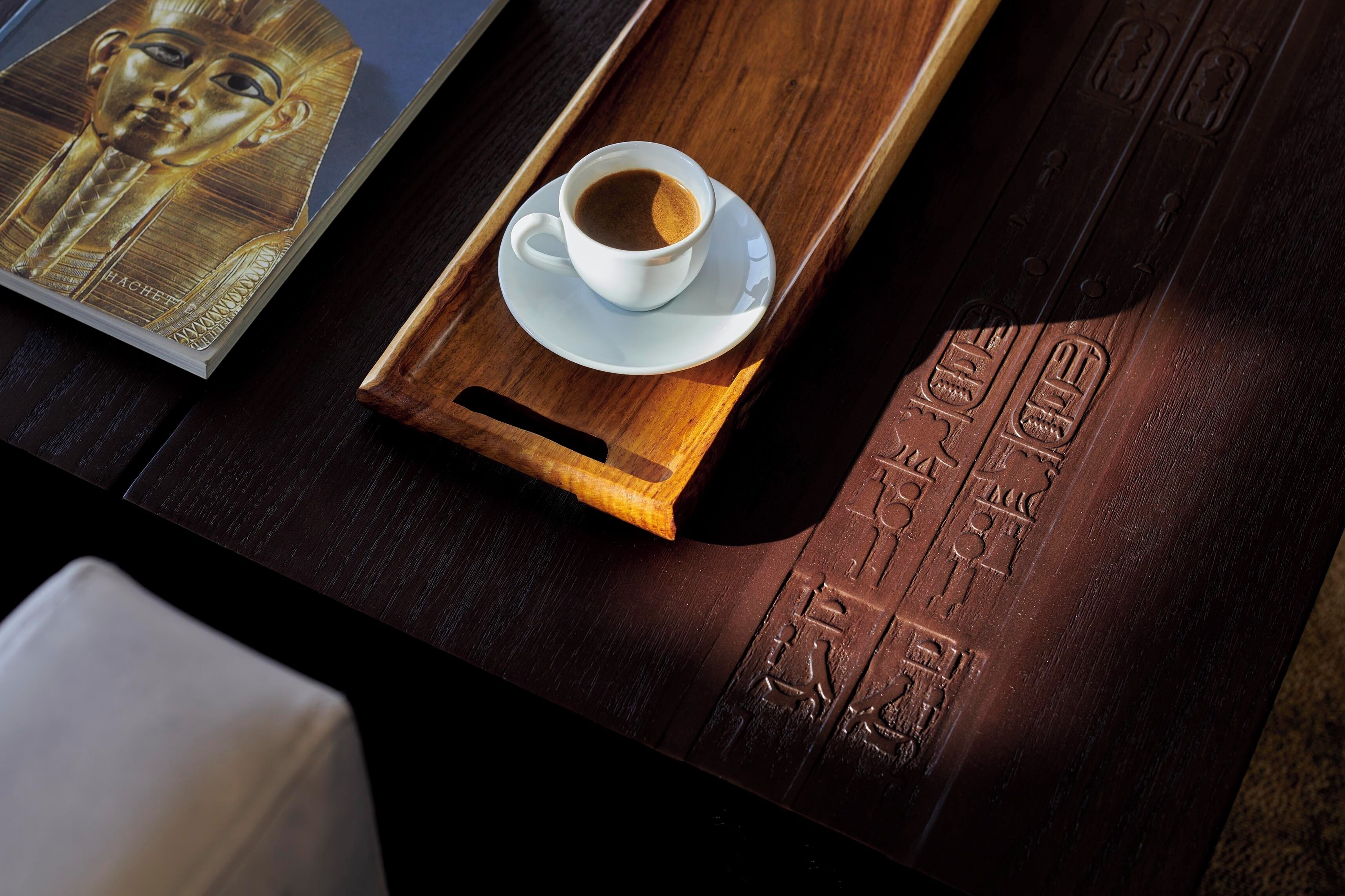 Una bandeja de madera con una taza de café y un libro sobre una mesa.