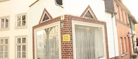 A building with a large window, a sign indicating a room is available, and a brick facade.