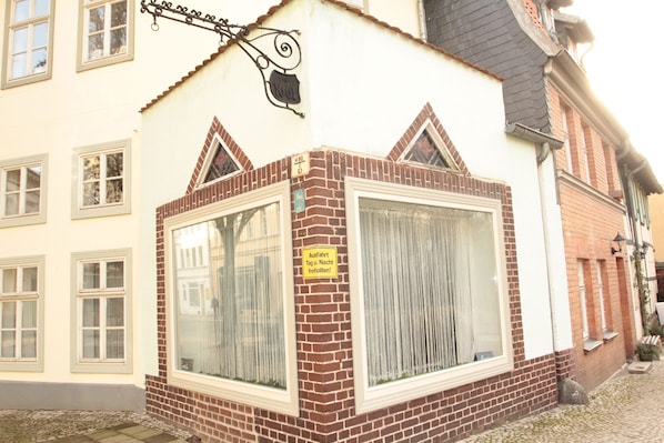 A building with a large window, a sign indicating a room is available, and a brick facade.