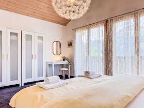 A bedroom with a bed, a desk, and a wardrobe.