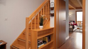 Eine Holztreppe mit einem weißen Topf auf der Zwischenebene und Büchern im unteren Fach.