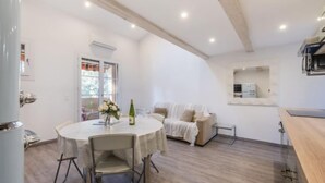Une cuisine moderne dotée d’un four à micro-ondes encastré, un coin repas avec une table ronde et des chaises, et un espace salon confortable avec un canapé.