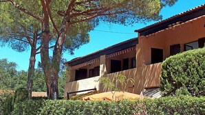 Un bâtiment à deux étages, doté d’un toit en tuiles, entouré de verdure et d’arbres.