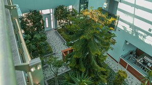 Un atrio de varios niveles con una cúpula de vidrio central, rodeado de plantas de interior y un diseño arquitectónico moderno.