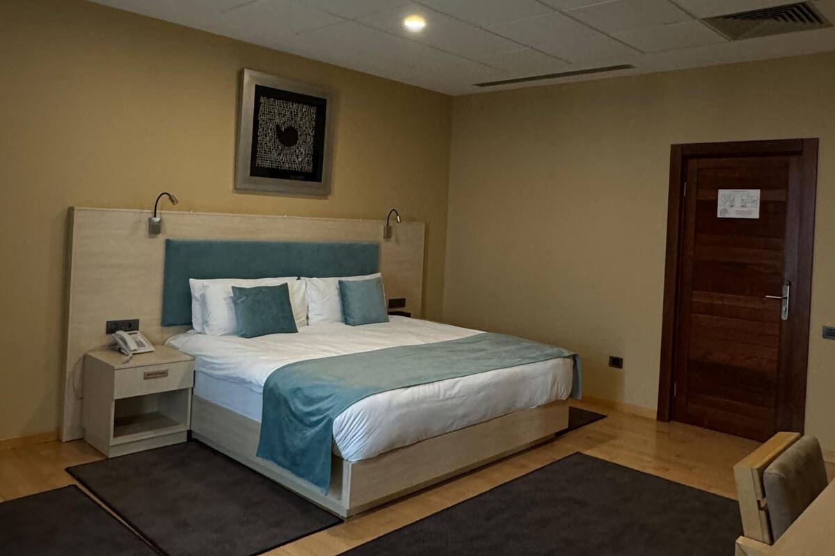Une chambre d’hôtel avec un lit, une table de chevet et une porte en bois.
