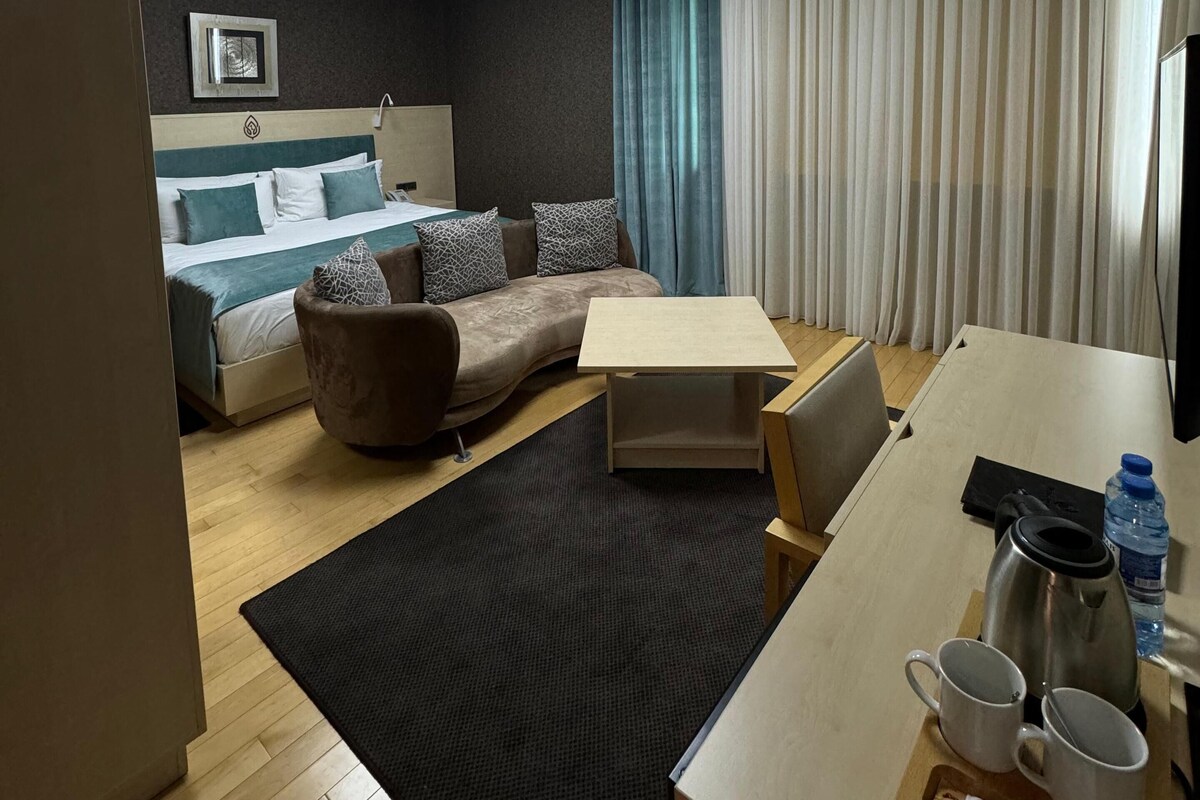 Een hotelkamer met een bed, een bank, een bureau en een salontafel.