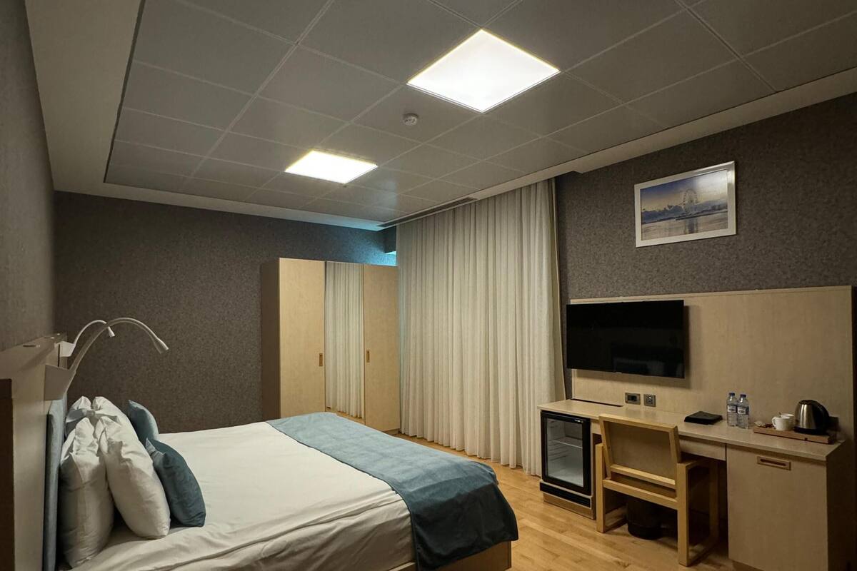 Une chambre d’hôtel moderne équipée d’un lit, d’un bureau, d’une télévision et d’une petite kitchenette.