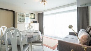 Un salon moderne comprenant un coin repas, un canapé, une lampe et une vue dégagée grâce à de grandes fenêtres.