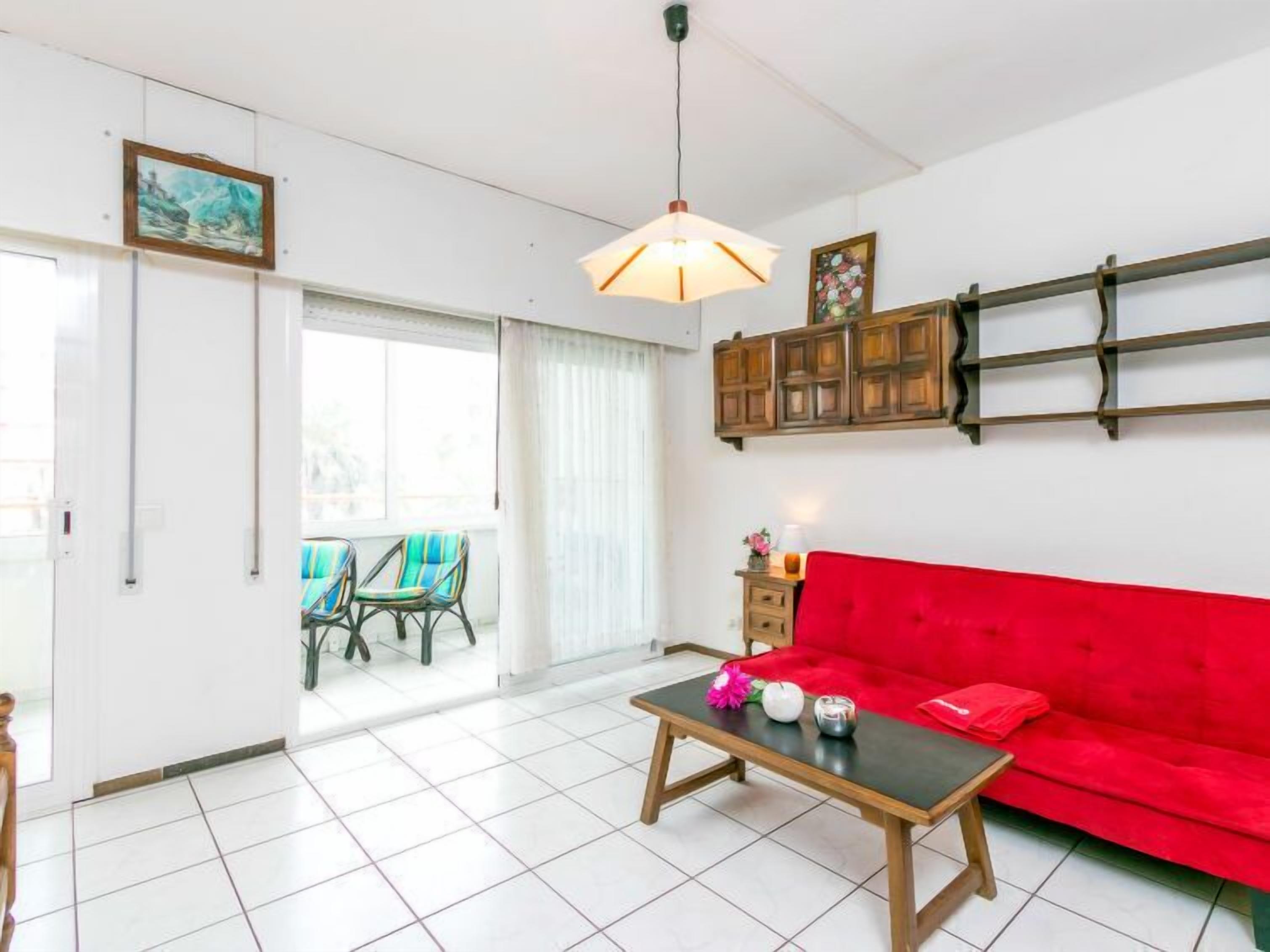 A living room with a red sofa, a wooden coffee table, and a hanging light fixture.