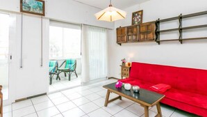 A living room with a red sofa, a wooden coffee table, and a hanging light fixture. - Roses Holiday Center by Interhome (Roses)
