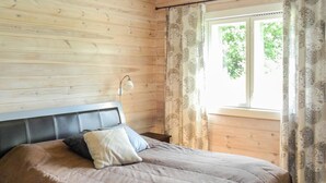 Una camera da letto con una testiera in legno, un letto con copriletto grigio e una finestra con tende a motivi.