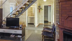 Un soggiorno moderno con pavimento in legno, una TV su un mobile, un camino e una scala che conduce a un'altra stanza.