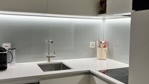 A modern kitchen with white cabinetry, a built-in sink, and a countertop with a kettle and utensils. - Residenza Chesa Margun 13-4 by Interhome (Silvaplana-Surlej)