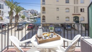 A balcony with a table set for breakfast, overlooking a marina with boats and buildings. - Porto Fino by Interhome (Empuriabrava)