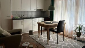 Eine moderne Küche mit weißen Schränken, einer schwarzen Arbeitsplatte und einem Essbereich mit einem Holztisch und Stühlen.