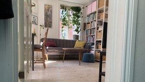 Een knus woongedeelte met een bank, een salontafel en een boekenkast vol boeken.
