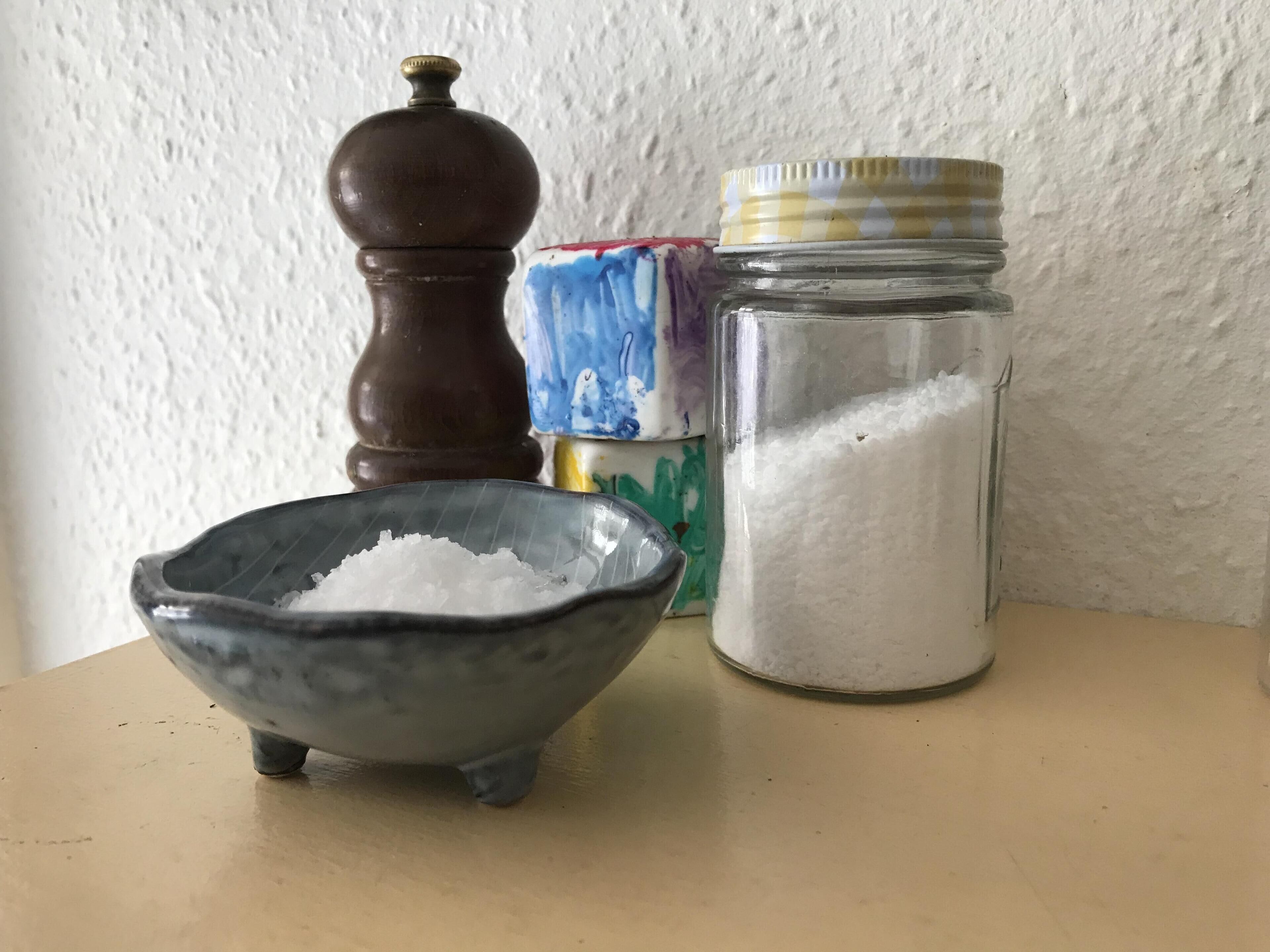 A small bowl of salt, a pepper shaker, and a jar of sugar on a table.