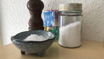 A small bowl of salt, a pepper shaker, and a jar of sugar on a table.