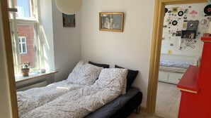 Een slaapkamer met een bed, een raam met een plant en een muur met diverse decoraties.