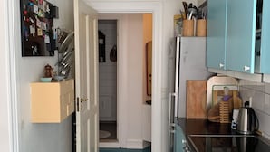 Een kleine keuken met blauwgroene vloeren, een hangende verlichtingsarmatuur en een koelkast.
