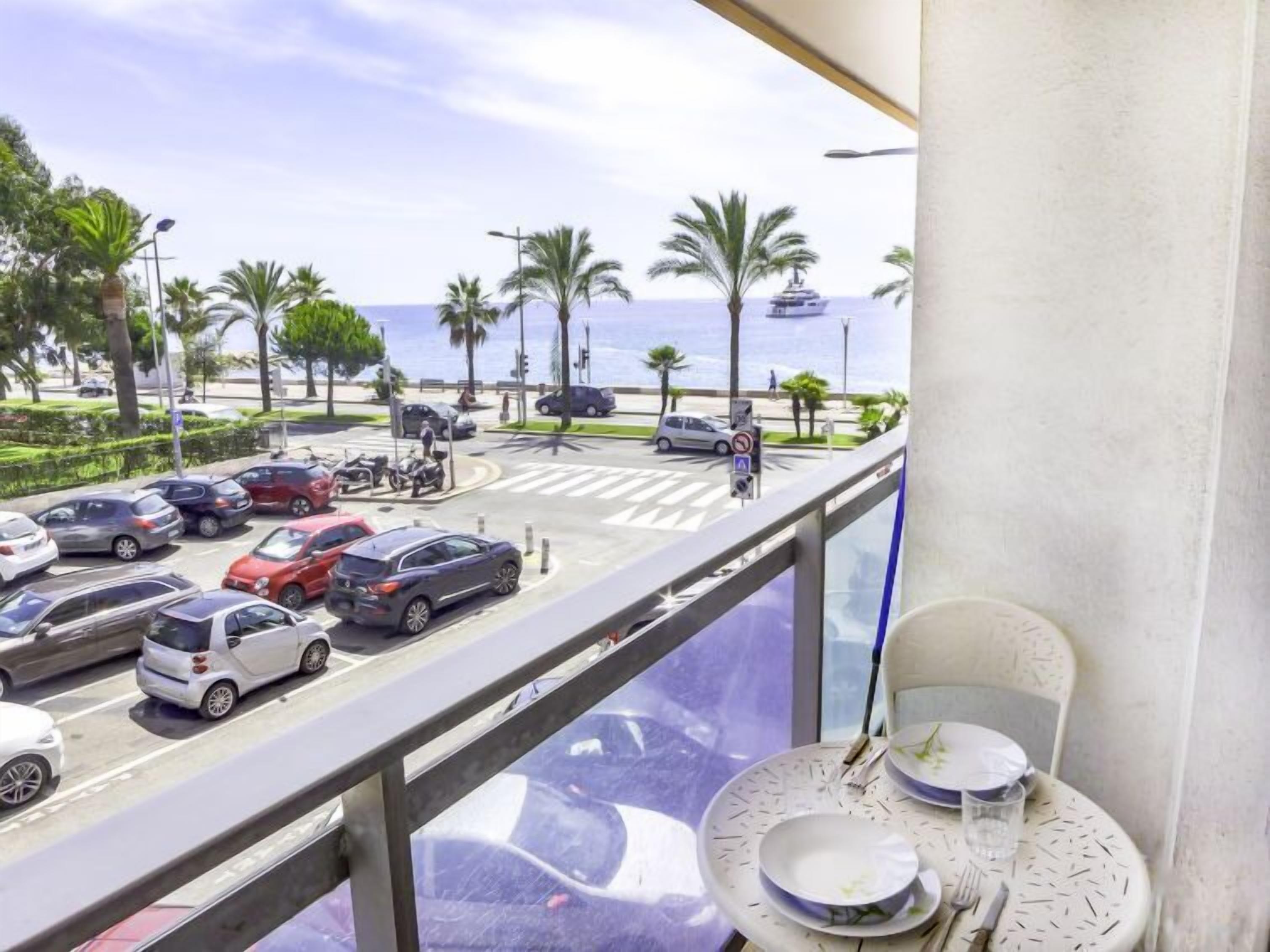 A balcony with a view of a parking lot and the ocean.