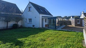 Een huis met een schuin dak, een glazen conservatorium en een verzorgd gazon.