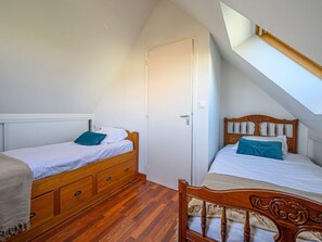 Een slaapkamer met twee eenpersoonsbedden, houten hoofdborden en een dakraam.