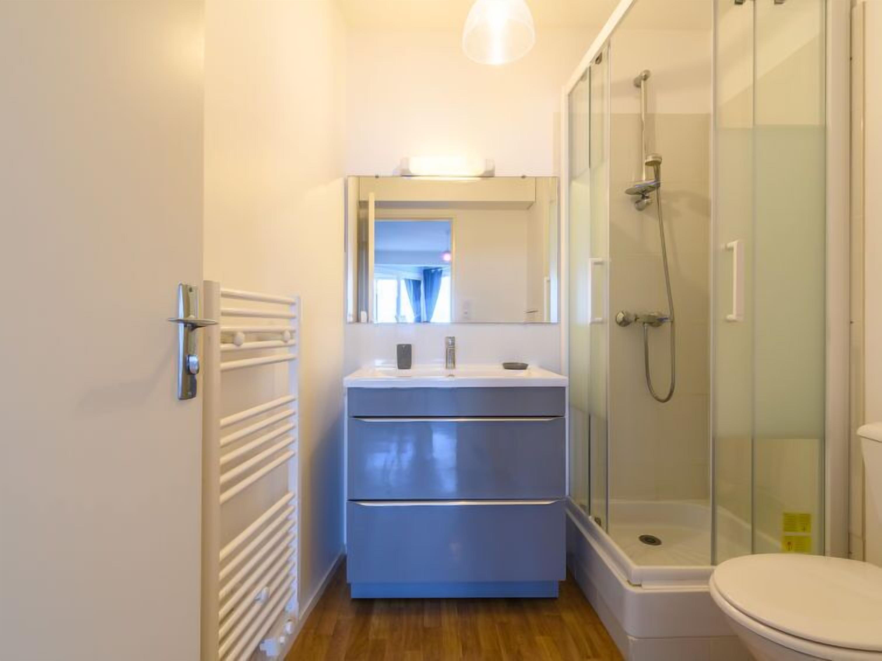 Un bagno moderno con doccia a vetro, un lavandino bianco con specchio sopra e un water.
