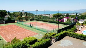 Een tennisbaan met vrij uitzicht op de zee en omliggend groen.