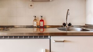 A kitchen with a stainless steel sink, two soap dispensers, and a white cabinet. - Valaisia 35A by Interhome (Nendaz)
