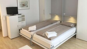 Een moderne slaapkamer met een bed, een televisie, een kledingkast en een schilderij aan de muur.