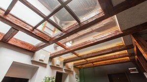 A modern interior with exposed wooden beams, a skylight, and recessed lighting. - Vendi Grand Square Residence (Sibiu)