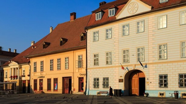 A historic building with a traditional European architectural style, featuring a prominent arched entrance and multiple windows. - Vendi Grand Square Residence (Sibiu)